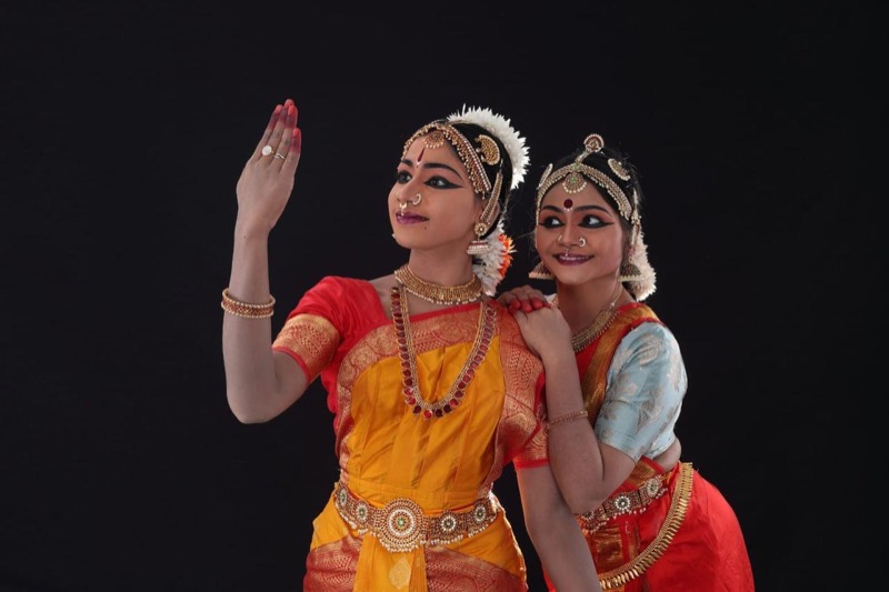 Two dancers posing together on black