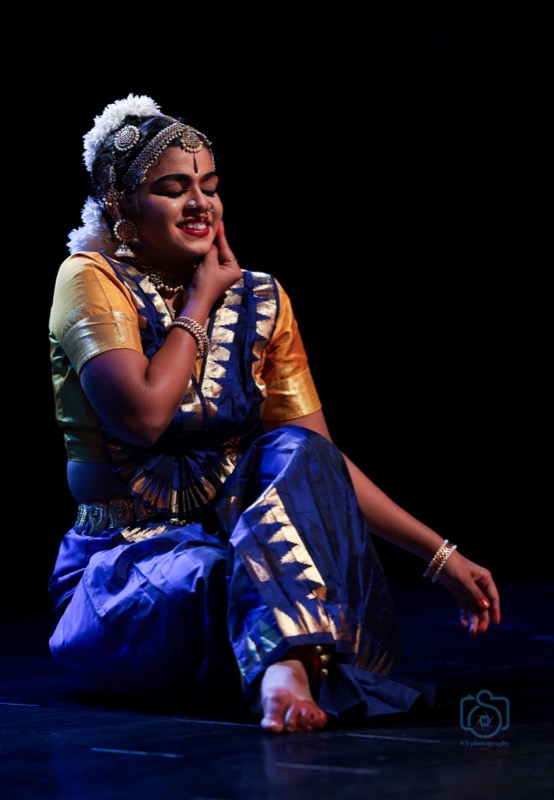 Dancer seated, smiling, hand on cheek