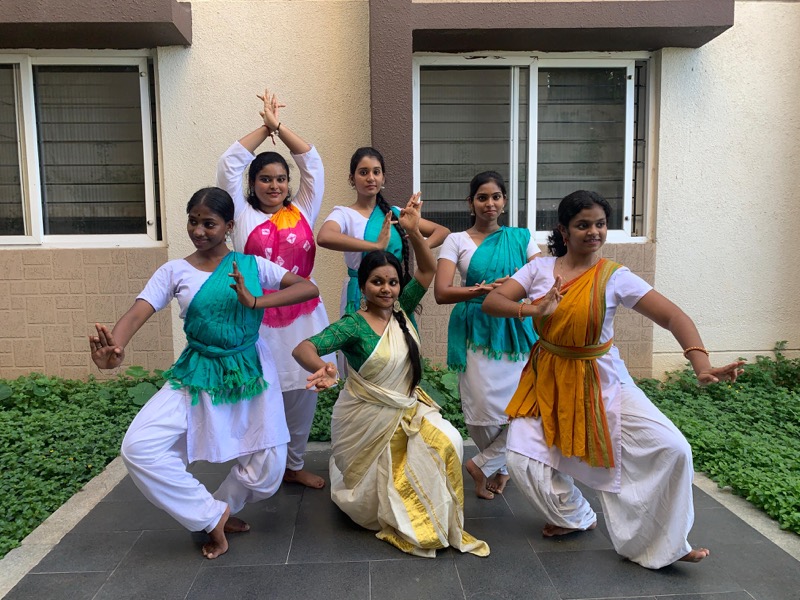 Five students striking poses in a courtyard